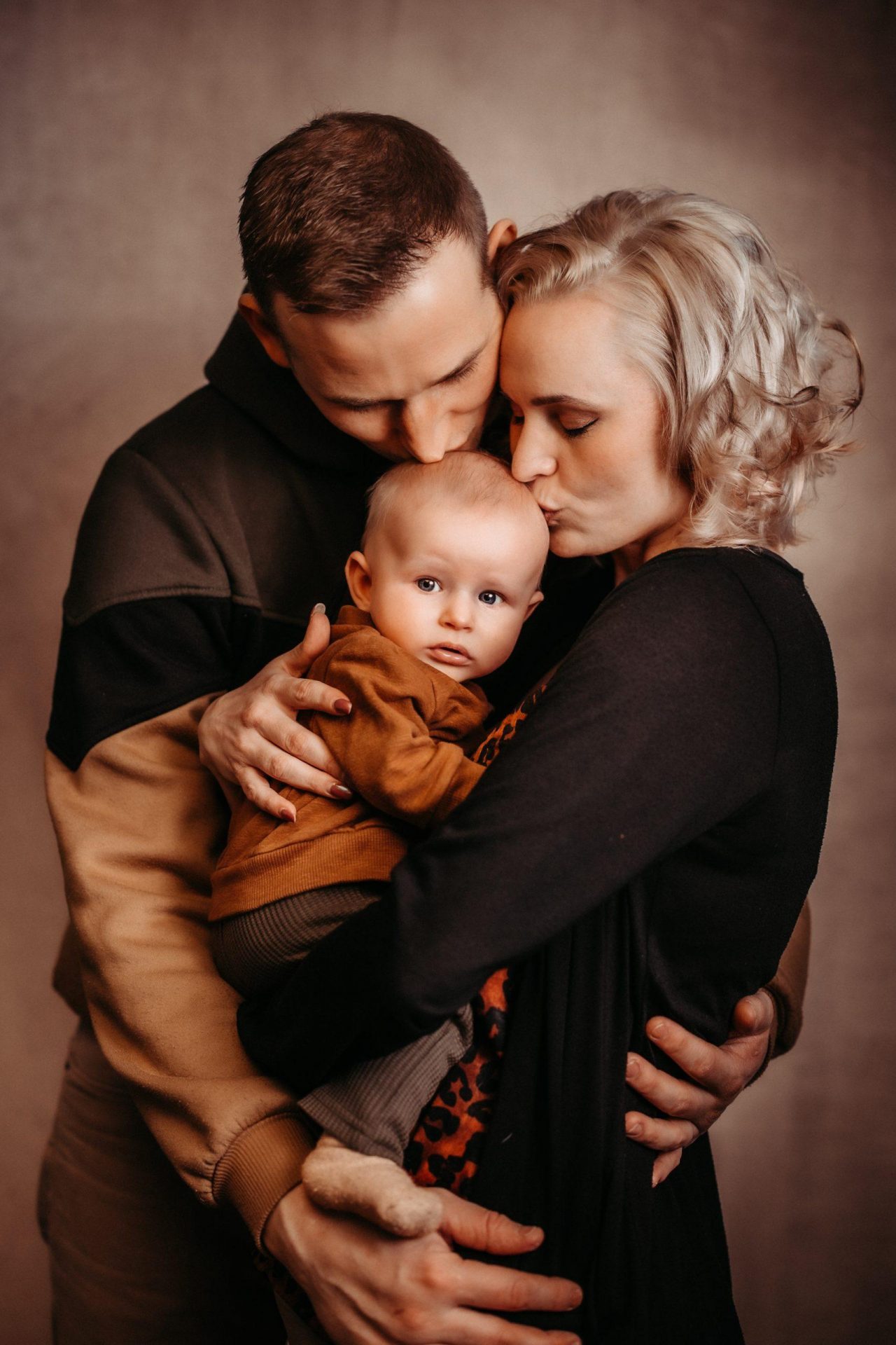 Fotostudio-Leutenberg_Babybilder Die jungen Eltern küssen auf den Kopf des Babys